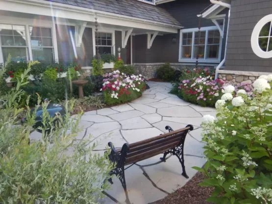 Fond du Lac irregular paving spreads across a courtyard walk between flower beds and a garden bench.