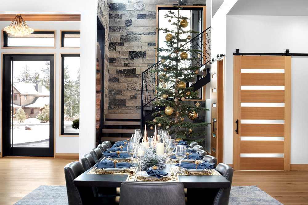 A full-height Charcoal chimney in split-face veneer rises behind a spiral staircase in the dining room.
