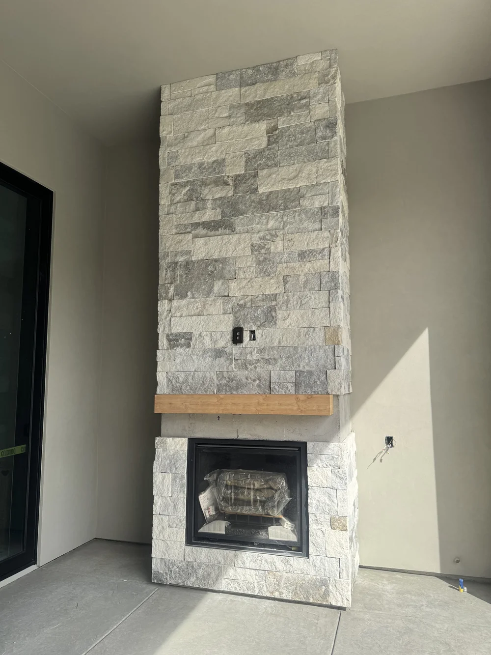 Blue climbs a chimney breast to the ceiling above a timber mantel and black firebox, dry stacked in cream and gray.