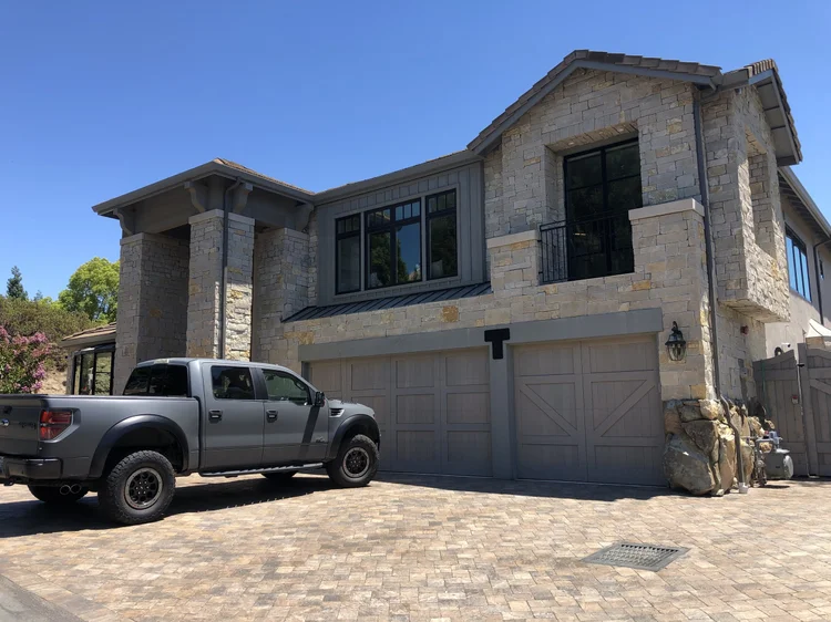Buff ashlar veneer in split and natural faces with dry-stack joints across a two-story entry facade.