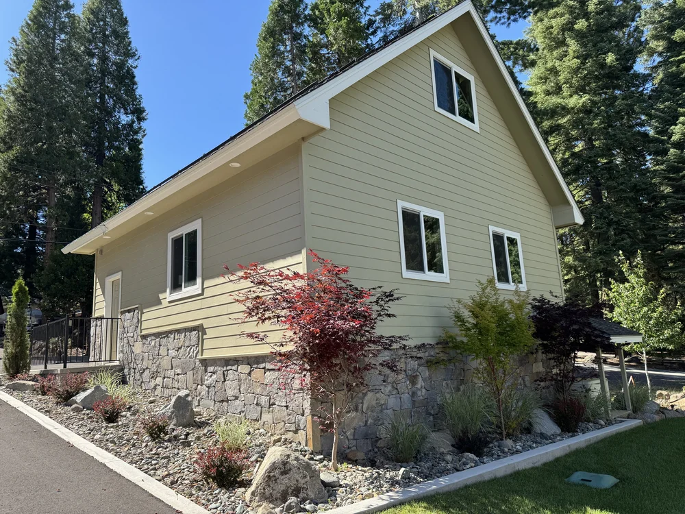 Split-face Gallatin River veneer along a facade elevation amid tall pines.