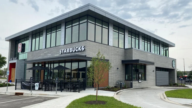 Plaza Gray panels band the ground floor of a two story Starbucks in even sawn courses, under a gray metal upper storey.
