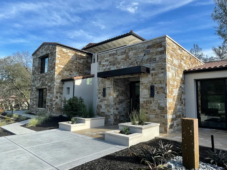 Monterey Estate ashlar veneer in split and natural faces with honed Indiana Limestone wall caps across a home facade, entry, and wall.