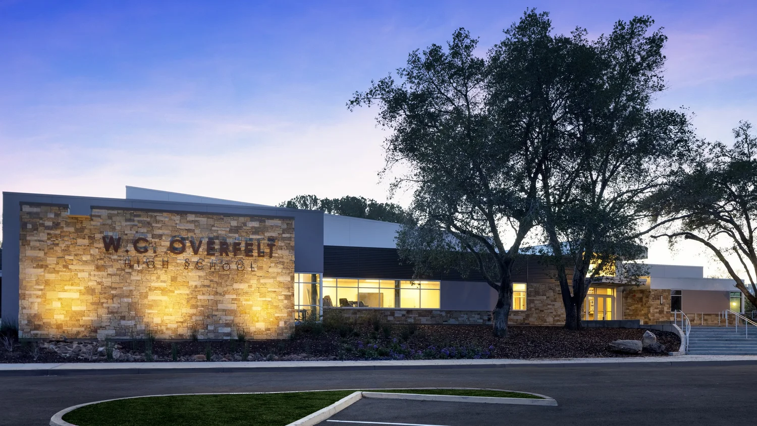 Monterey Estate ashlar veneer and honed Indiana Limestone wainscot caps wrapping the facade and entry of a school building.