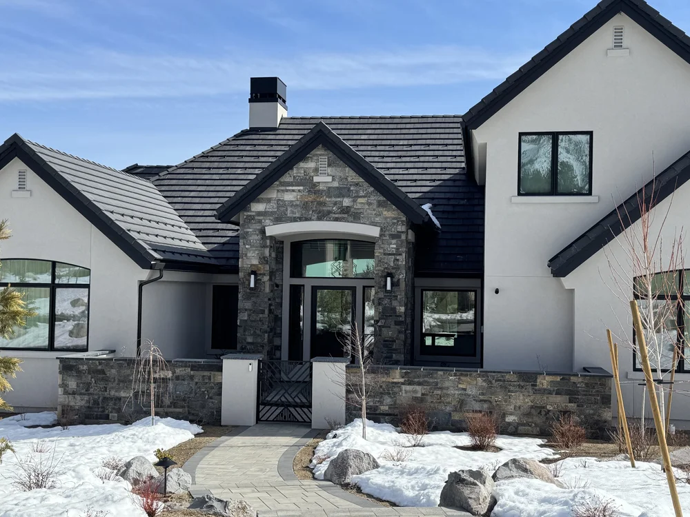 Graphite ashlar marks the arched entry and the low garden wall running out from it across the snow.