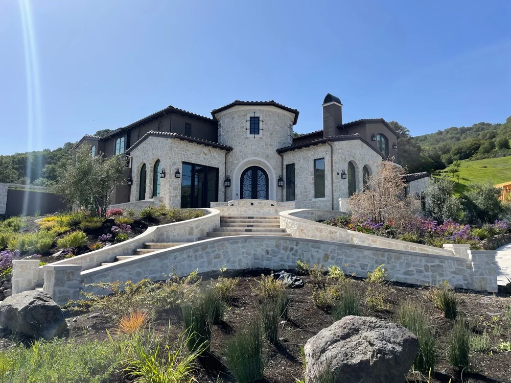 Tuscany field veneer framing a facade and entry with Indiana Limestone pavers, wall caps, and column caps across the patio and staircase.