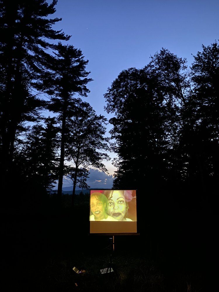 a screen showing a videopoem still of Samiya Bashir's face set against a backdrop of a mountain sunset