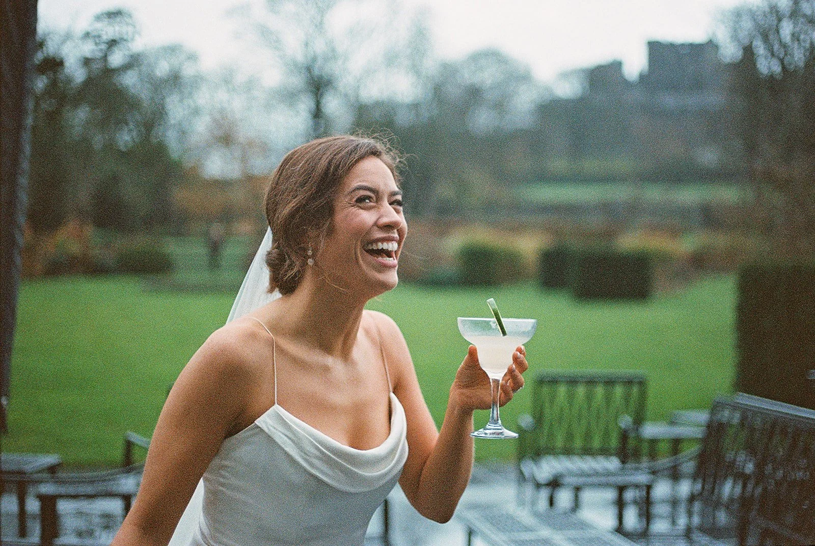 Bride laughing with a cocktail on the lawn at Cashel Palace, photographed on film