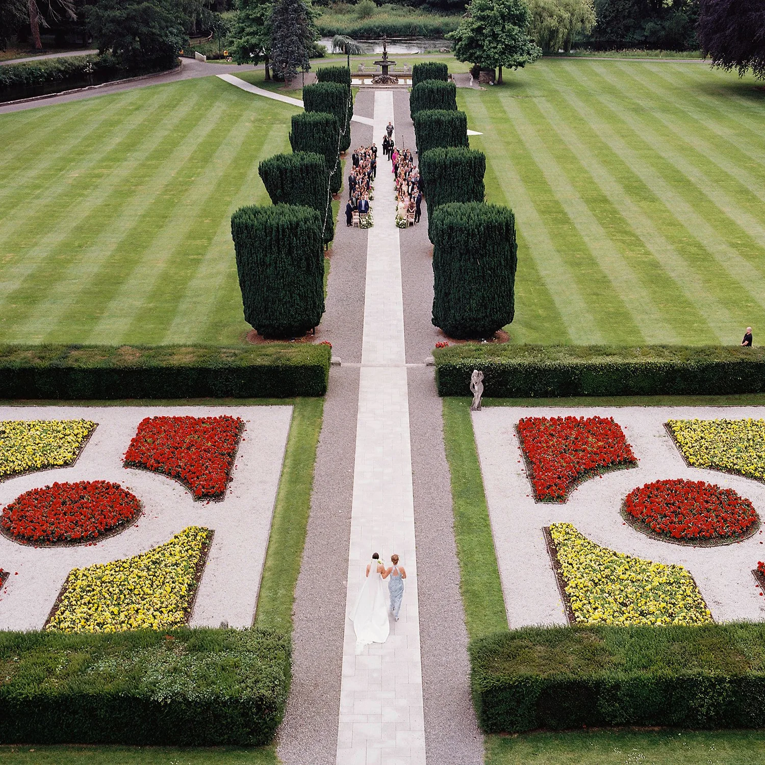 Aerial film photograph of a couple walking the long path through the formal gardens at The K Club