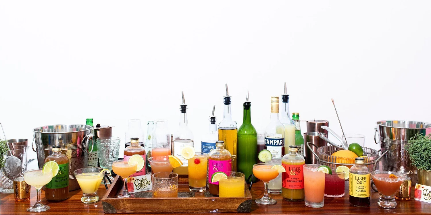 A Drink Slingers bar laid out end to end with spirits, mixers, garnish and finished cocktails