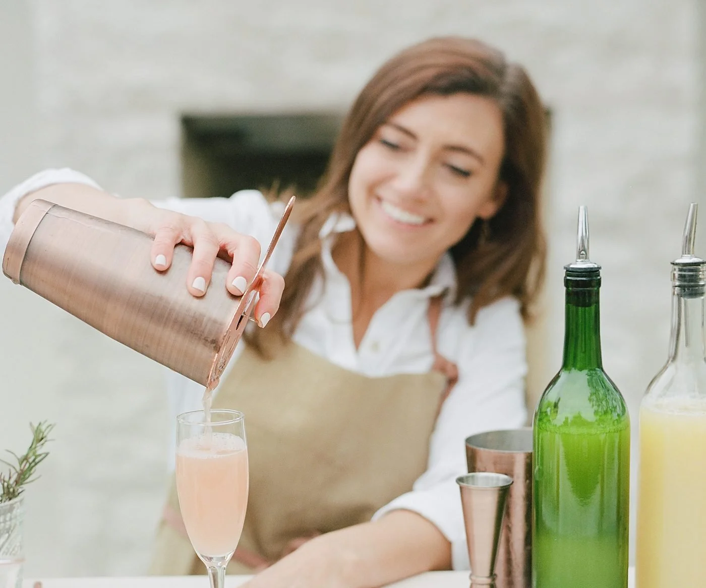 A Drink Slingers bartender smiling while she shakes a cocktail behind the bar