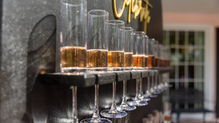 Flutes of champagne lined up on a black champagne wall