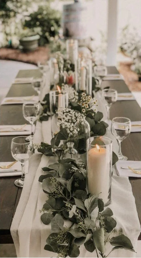 A reception table with candles, flowers and place settings