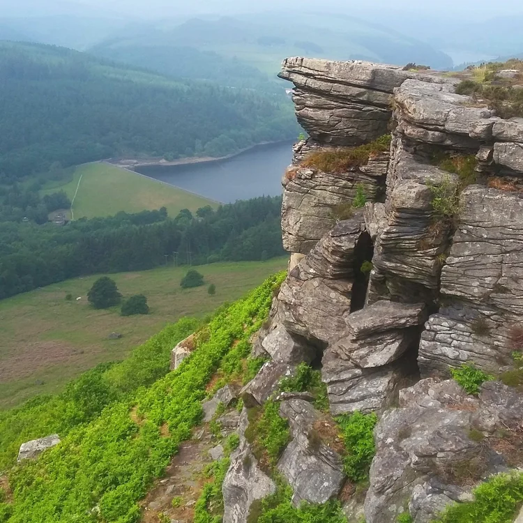 A large steep rocky outcropping on the right rises above the heathland.