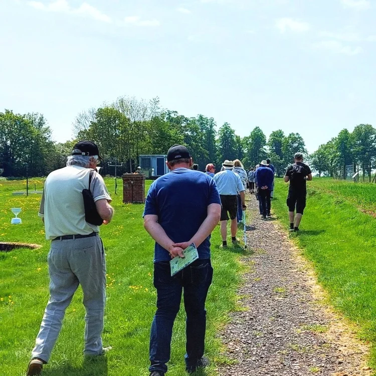 Photo taken of the back of a group of people walking down a path at Park Grass