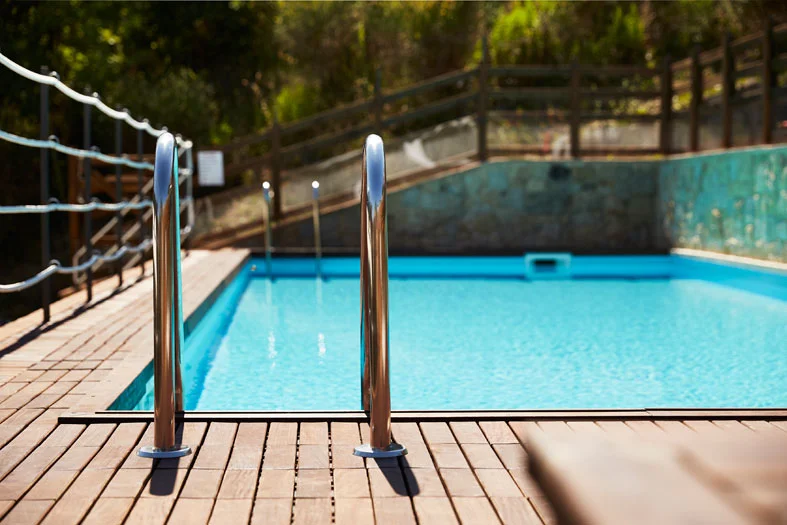 Zwembad met helder water en dubbele roestvrijstalen trap