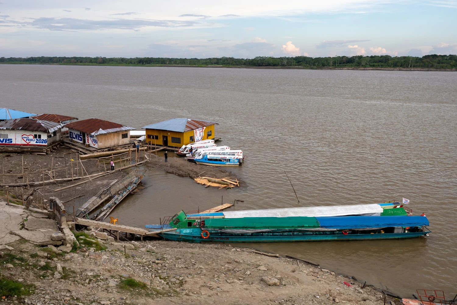 A long passenger boat moored beside riverside houses in Indiana, Peru