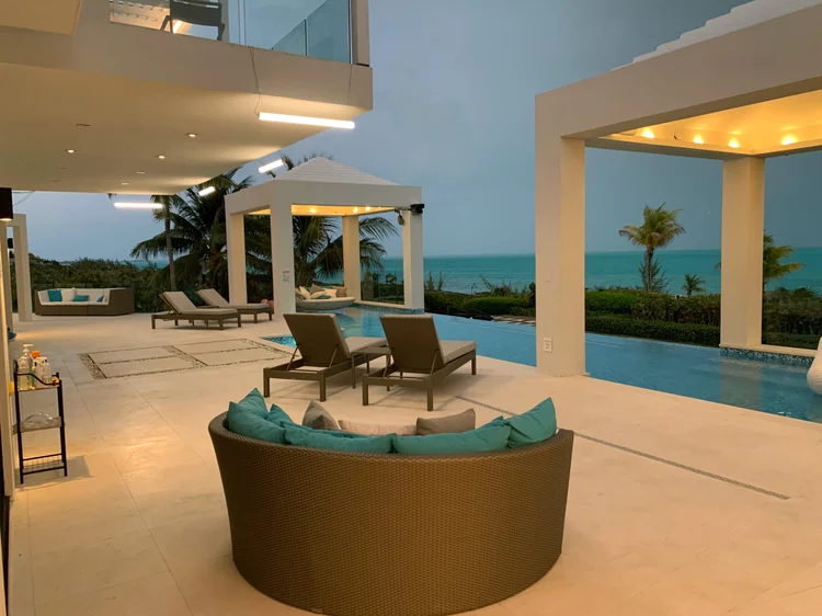 Oceanfront terrace and infinity pool at dusk with pergola and recessed lighting at the Turks & Caicos villa
