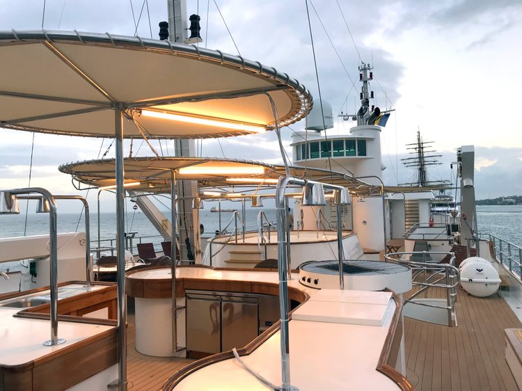 Top deck of a yacht at dusk with warm LED lighting beneath the shade canopies, installed by The Camera EYE