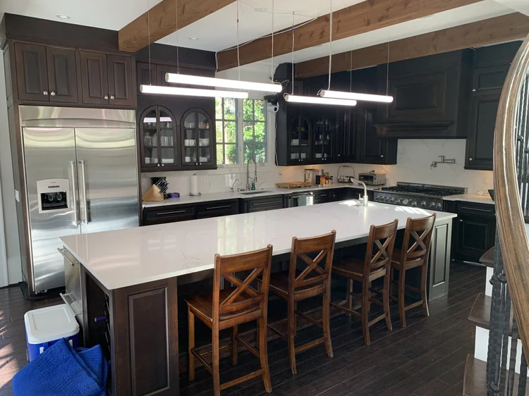 Kitchen with a waterfall island and suspended linear LED pendants in the Black Ink Atlanta house