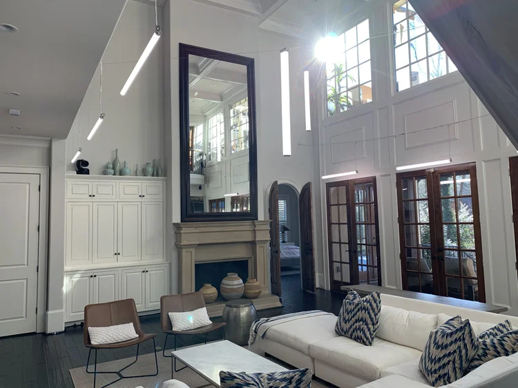 Double-height living room with suspended linear LED fixtures and a camera position in the Black Ink Atlanta house