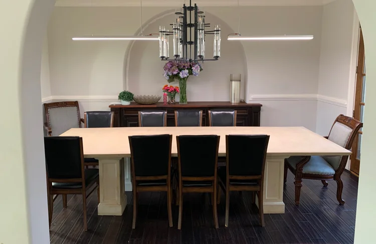 Formal dining room with a sculptural chandelier and flanking linear LED pendants in the Black Ink Atlanta house