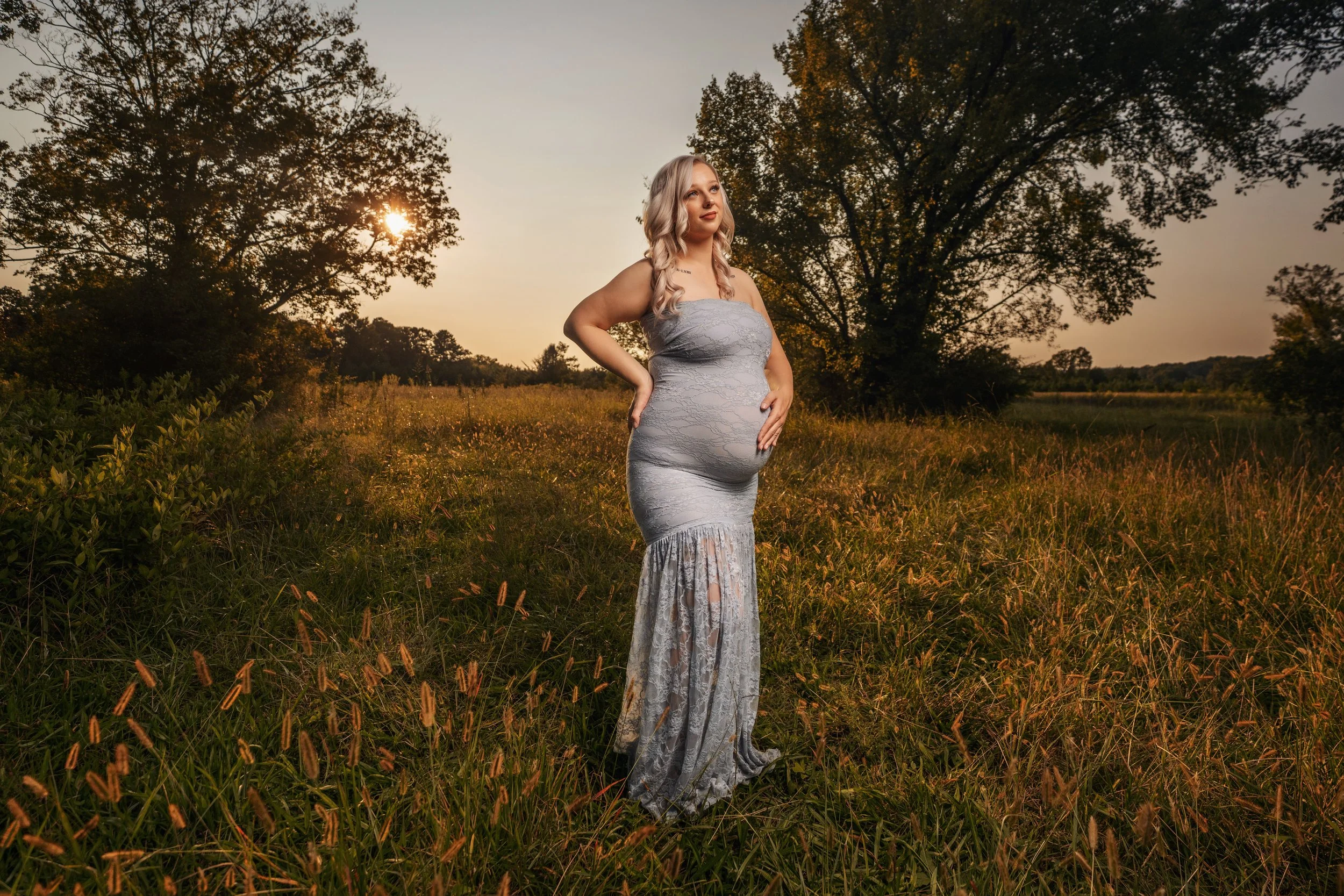 Expectant mother standing in a sunlit Chattanooga field at golden hour