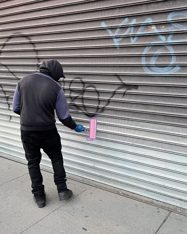 A CDS crew member removing graffiti from a security gate