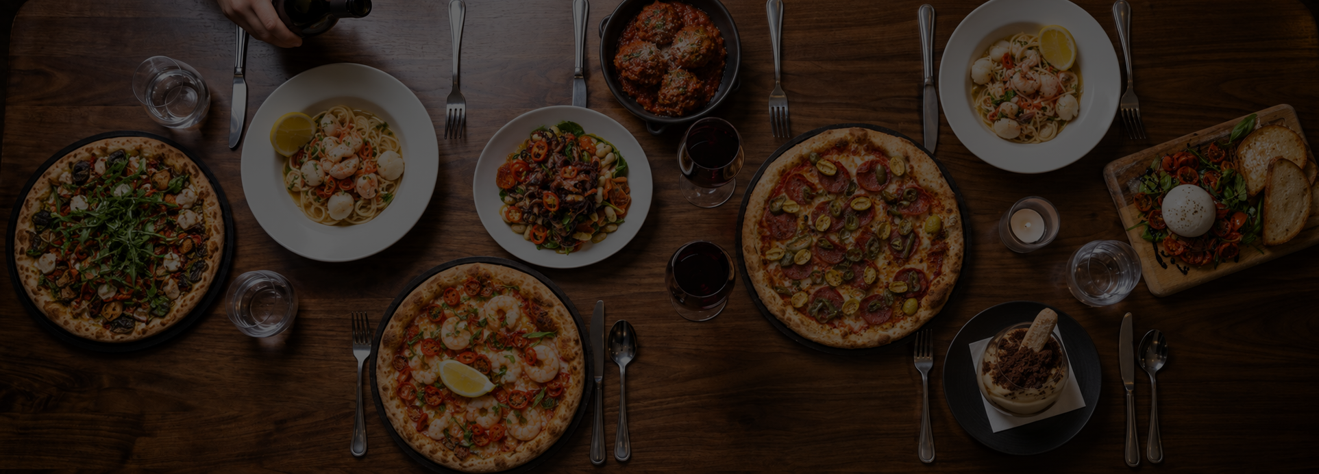A warm Italian spread of pizza, pasta, antipasti and wine in a cosy restaurant