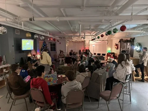 Students and leaders gathered around tables in the AY youth room at a Christmas gathering