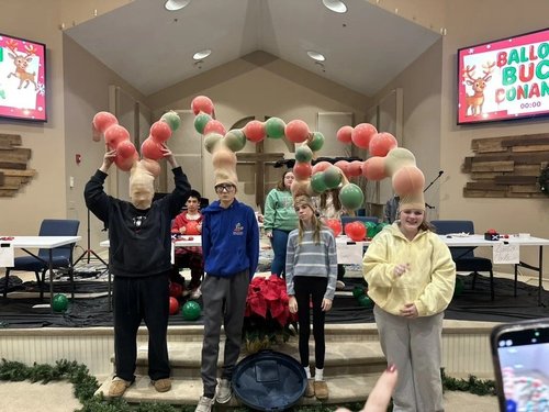 Students playing a balloon-antler game at an AY Christmas gathering