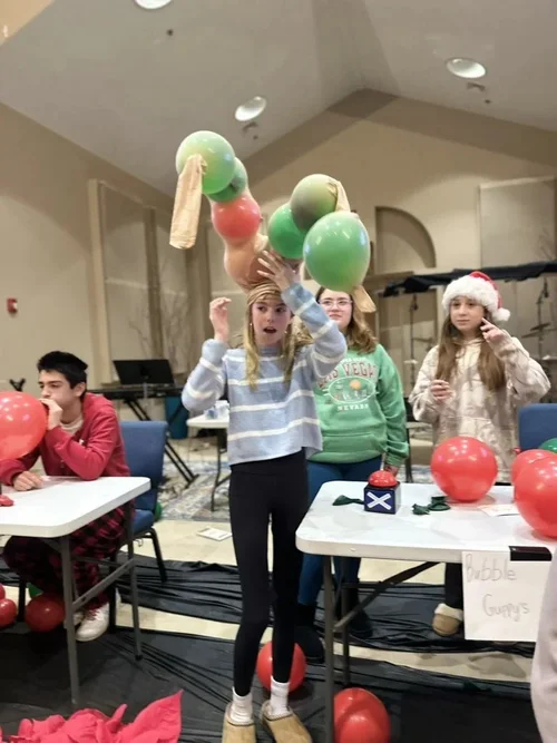 Students assembling balloon antlers together during an AY Christmas game