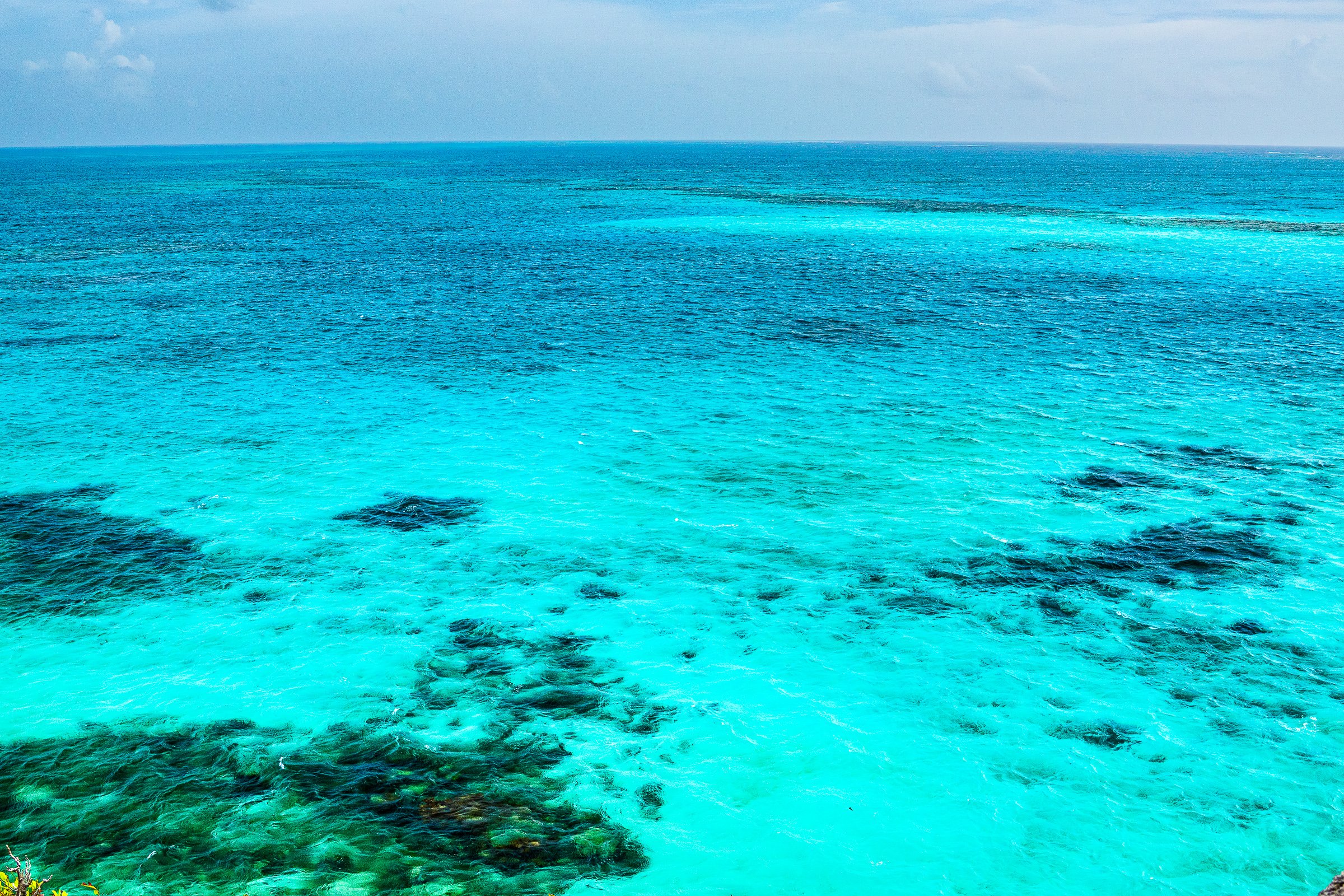 Tropical turquoise waters and darker reef patterns extend beneath the horizon.