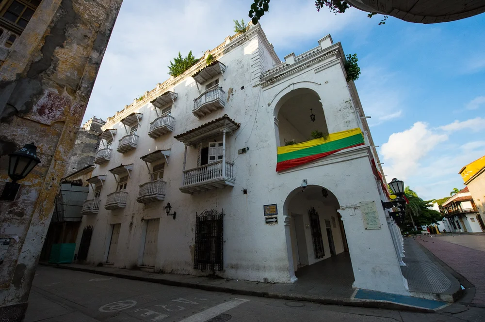 A white colonial facade with arched balconies carries the colors of the Colombian flag.