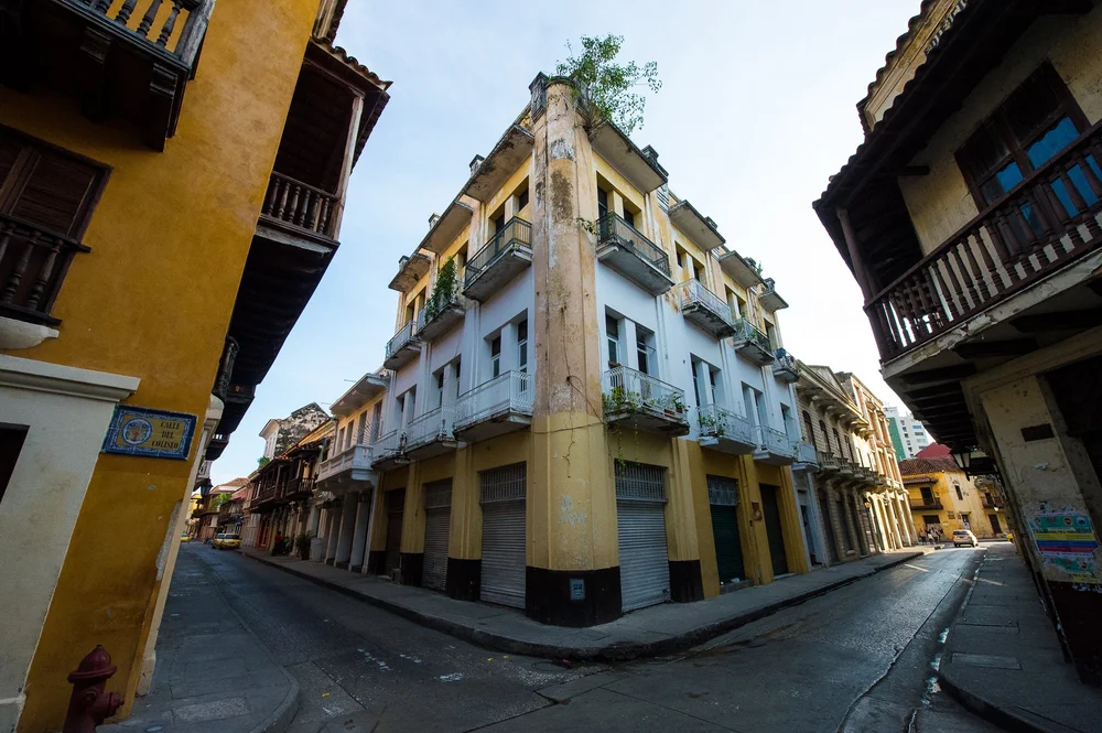 A weathered corner building layers pale walls, wooden balconies and traces of old paint.