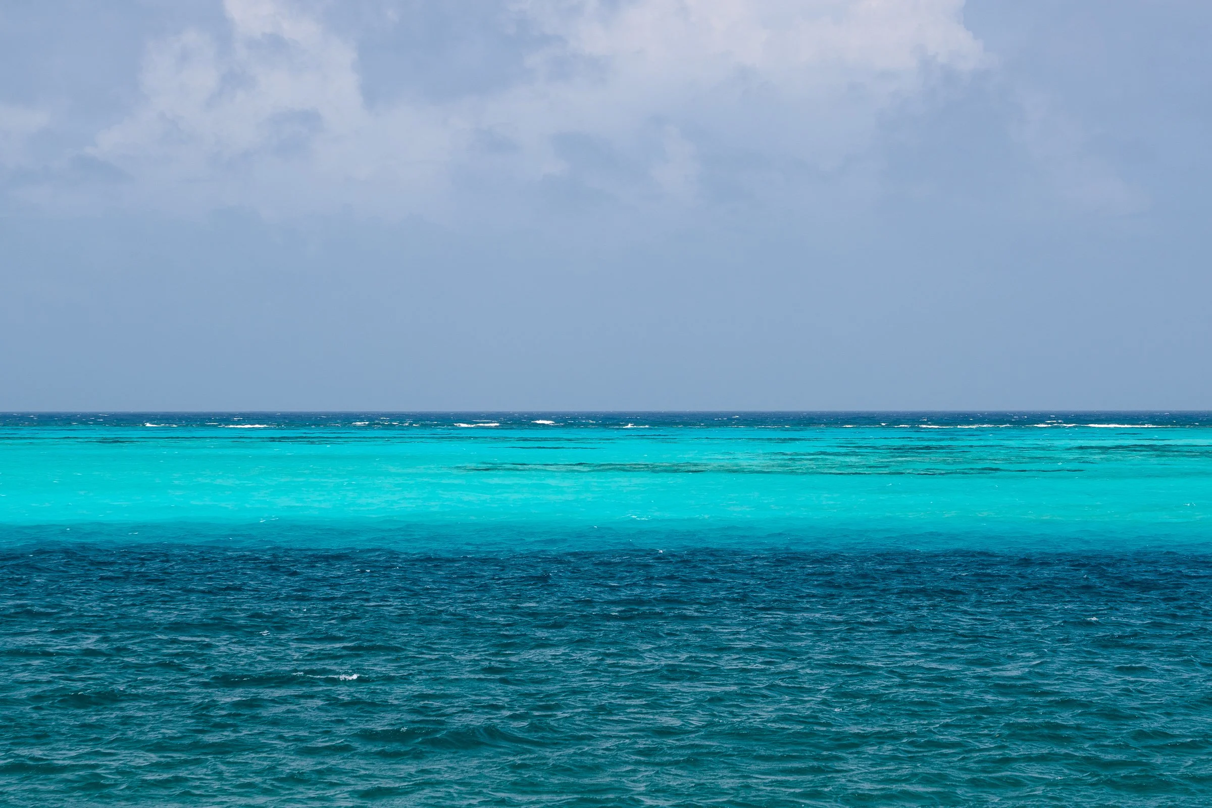 Bands of teal, electric turquoise and deep blue Caribbean seawater stretch to the horizon.