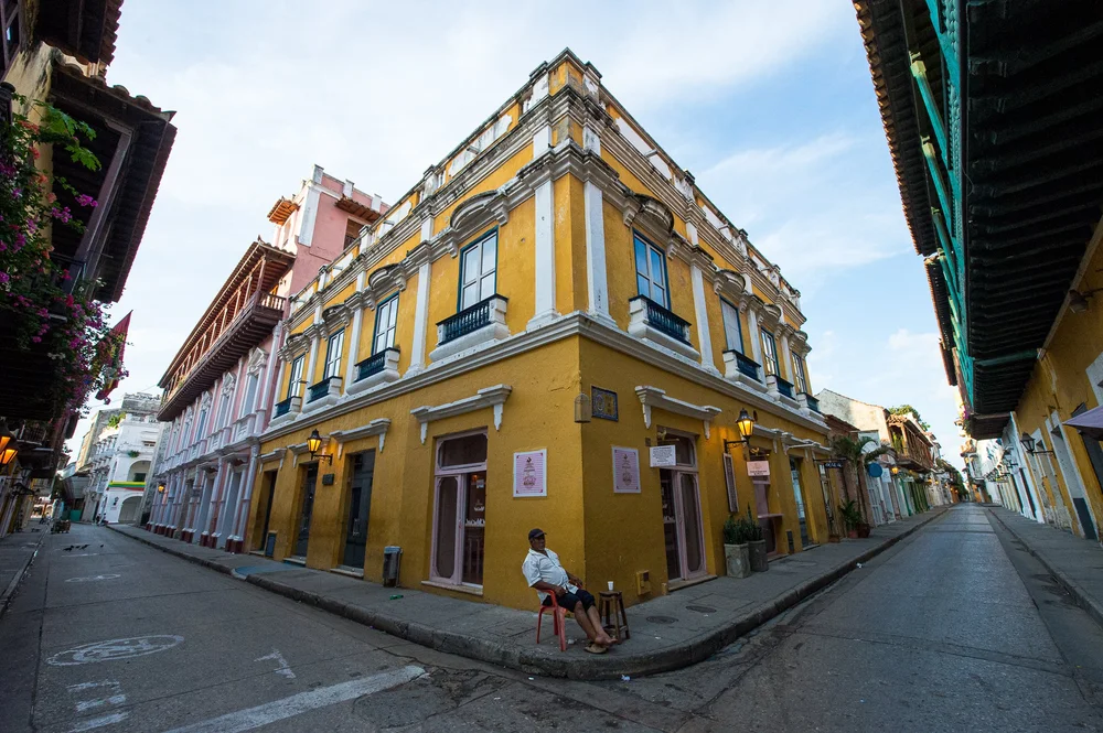 A cyclist passes an ornate yellow and white corner building in Cartagena.