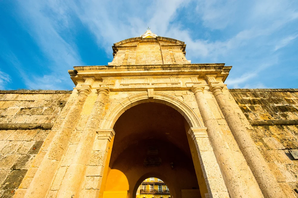 An old stone archway frames the shaded passage into Cartagena's historic city.
