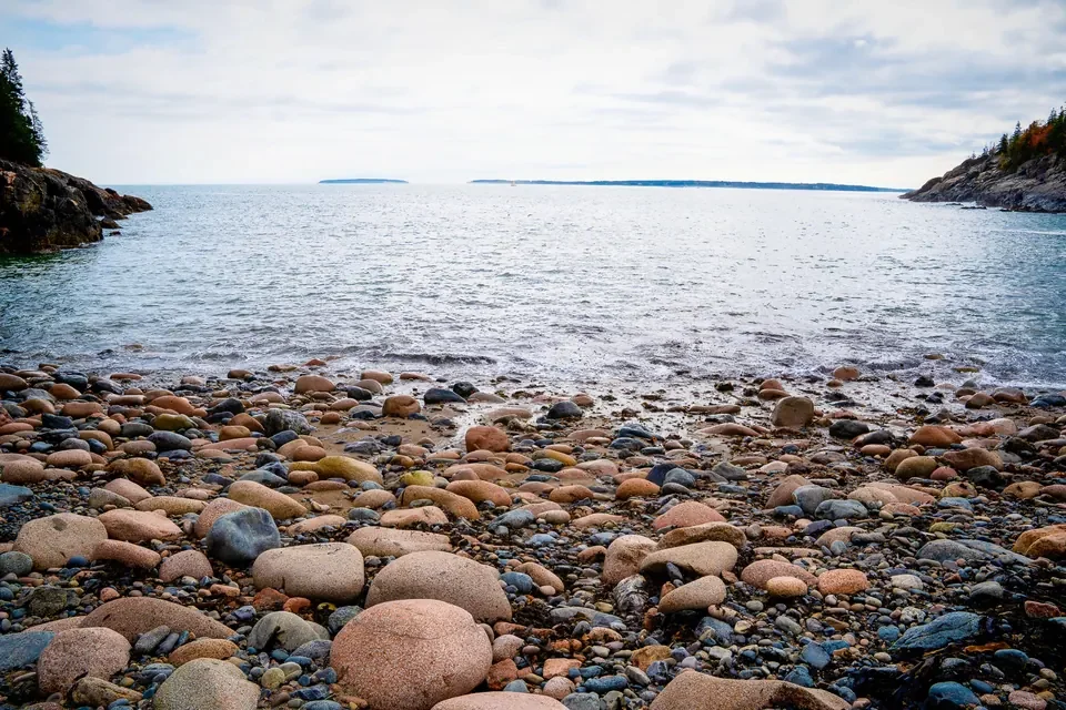 A broad Atlantic horizon rises beyond a natural beach of rounded stones.