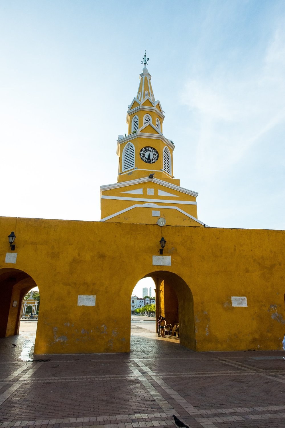 A vertical view of Cartagena's clock tower and its arched gateway beneath a bright sky.