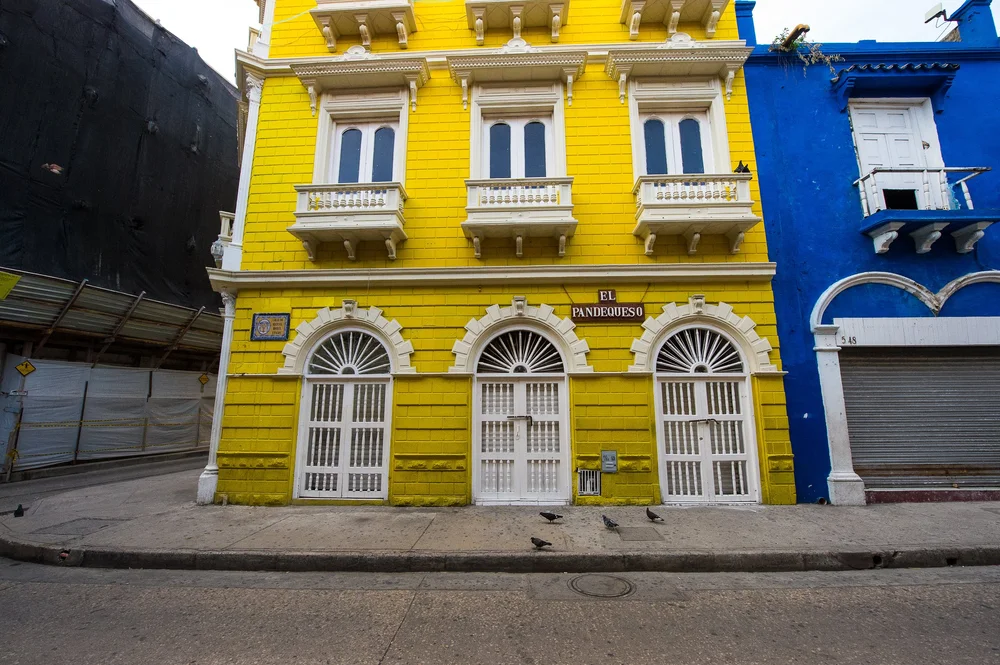 White arched window grilles and decorative moldings contrast with a brilliant yellow facade.