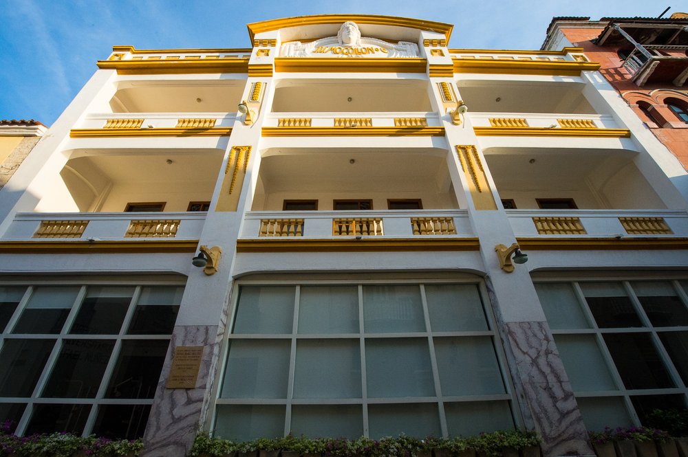 Cream and yellow architectural details frame a tall facade with elegant open balconies.