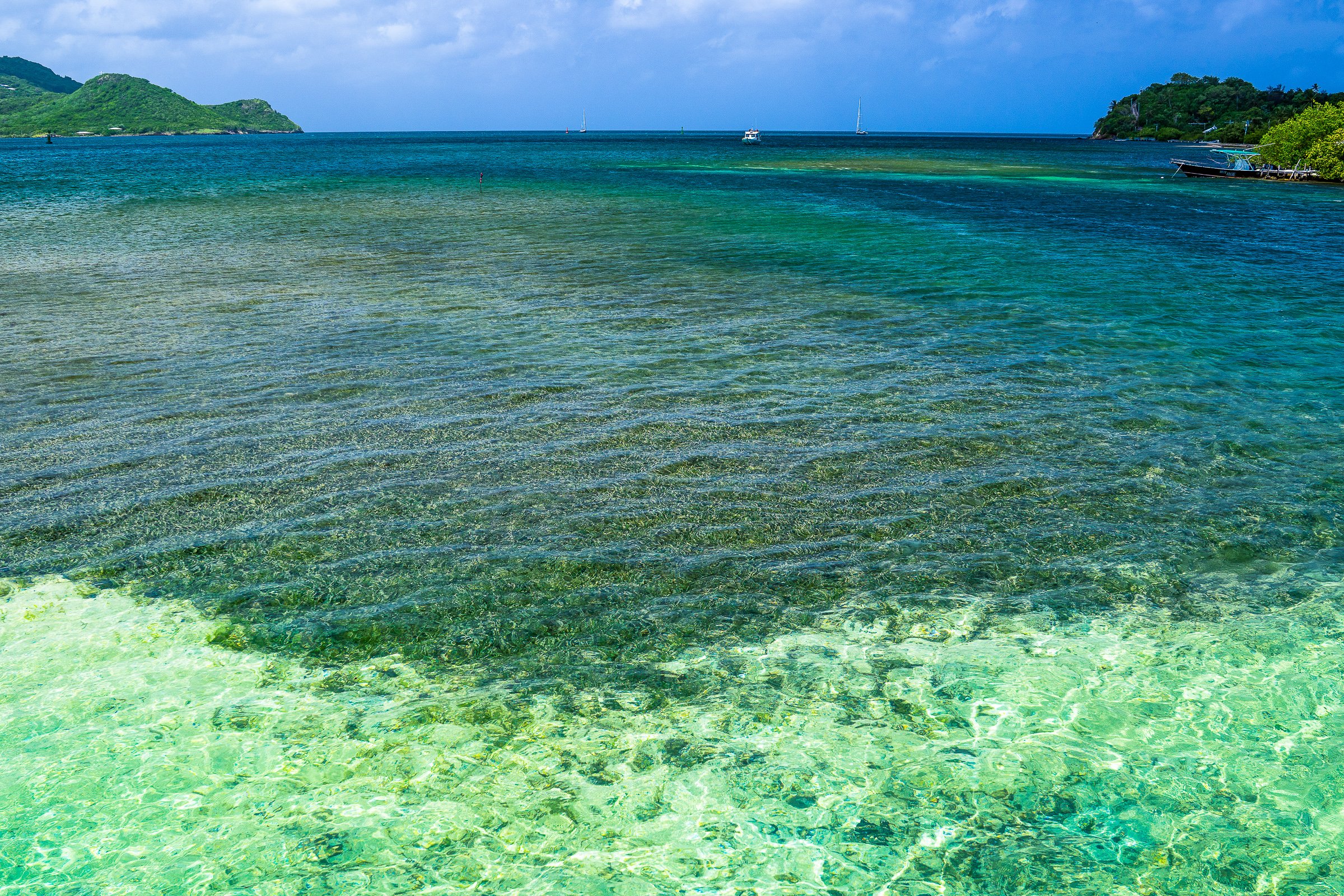 A transparent turquoise lagoon reveals its seafloor beneath a green headland.
