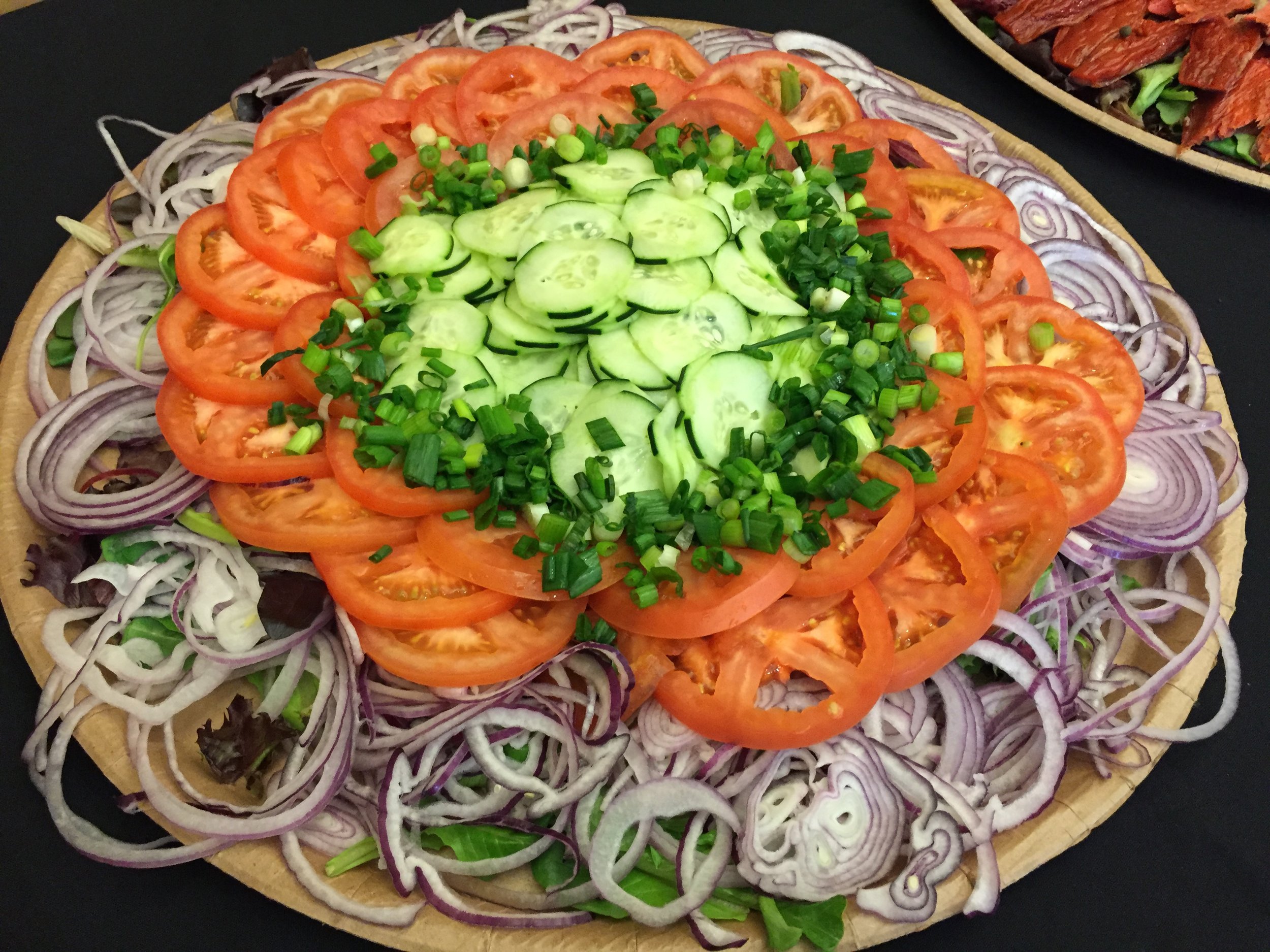 Fresh vegetable platter with sliced tomatoes, cucumbers and red onions