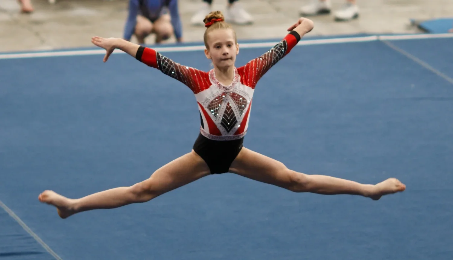 Gymnast performing a split leap during a floor routine.