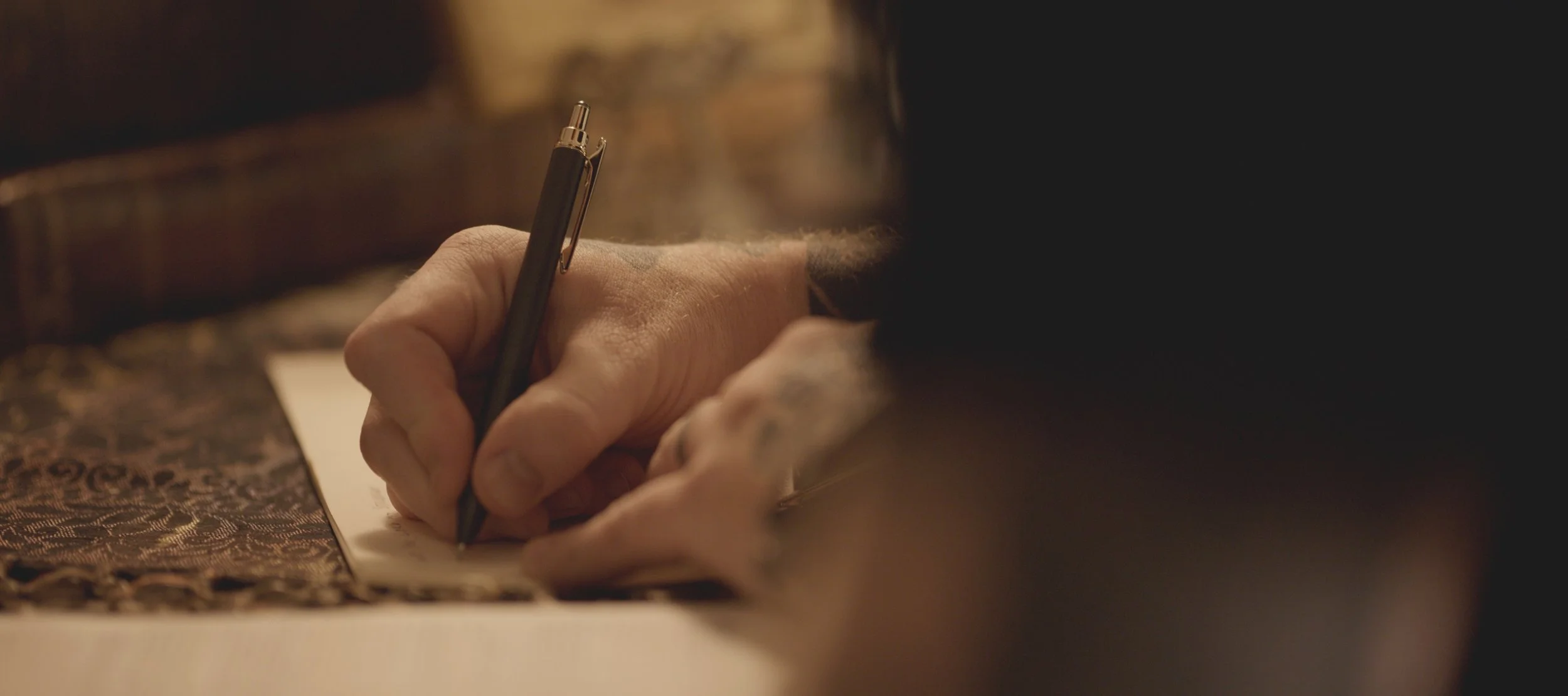 Stephen McWhirter’s hand writing with a pen beside an open Bible