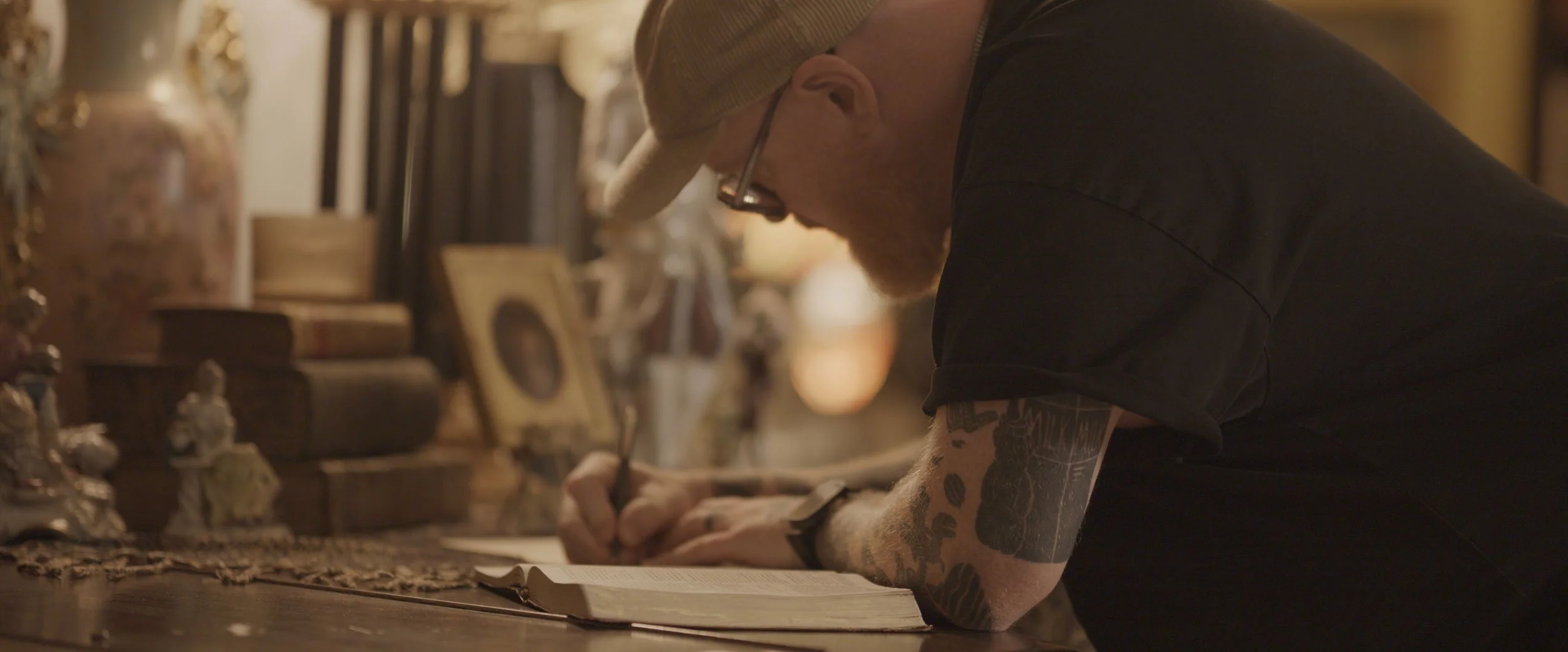 Stephen McWhirter writing in a journal beside an open Bible