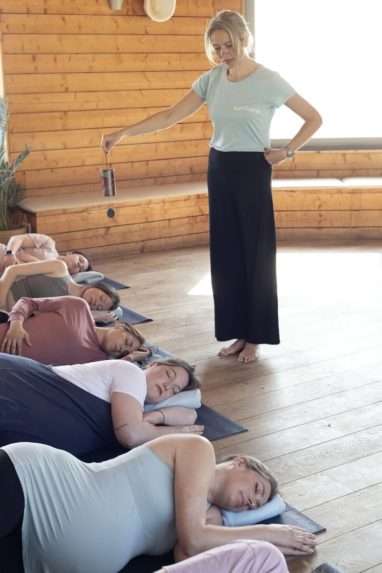Teacher using a chime bar over a class in deep relaxation