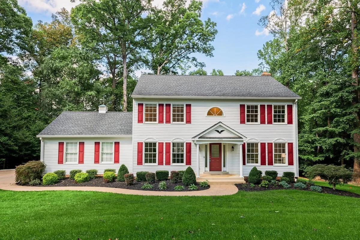 White colonial front exterior with red shutters