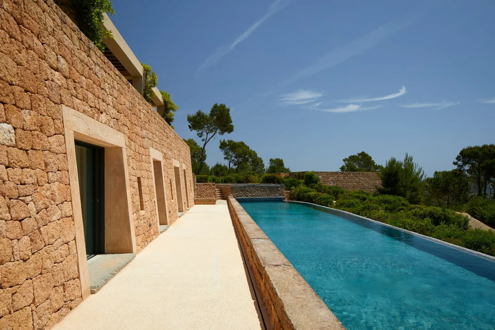 Piscina longitudinal junto a la fachada de piedra de Sa Guarda.